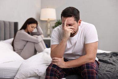 Offended couple ignoring each other after quarrel in bedroom, selective focus. Relationship problems