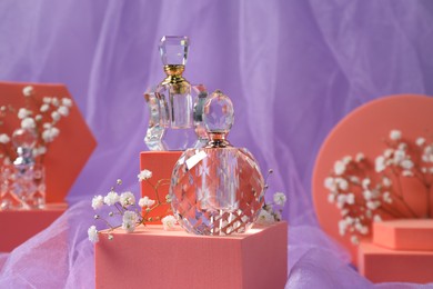 Stylish presentation of perfume bottles and gypsophila flowers on light violet fabric