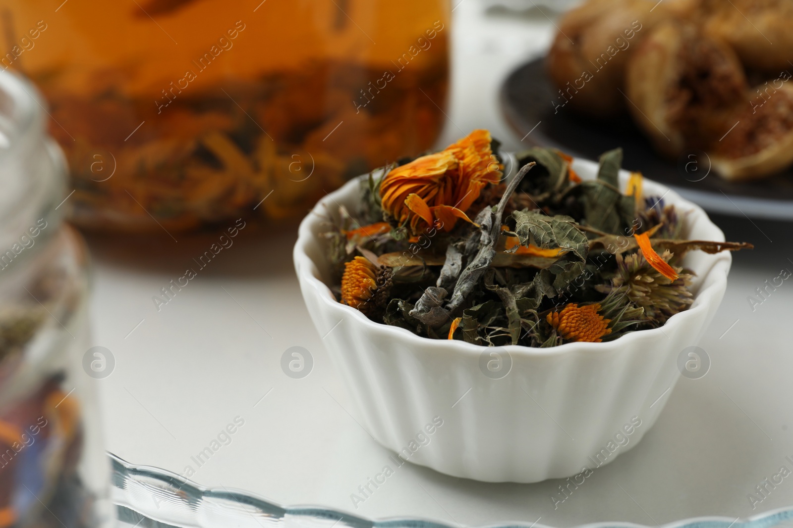 Photo of Dry herbal tea in bowl on tray, closeup