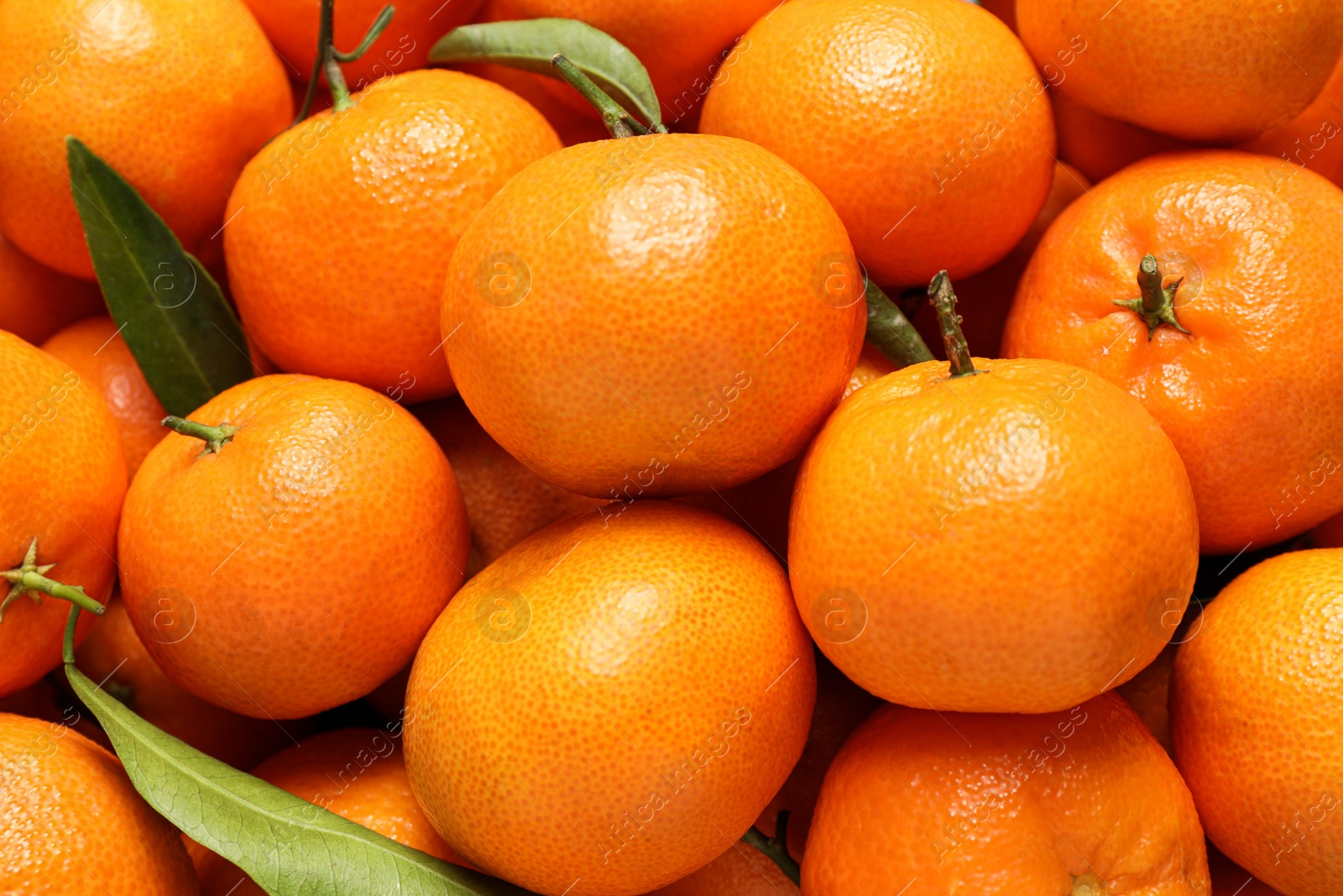 Photo of Fresh ripe tangerines with leaves as background, top view. Citrus fruit