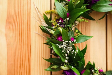 Photo of Beautiful wreath made of flowers and leaves on wooden background, closeup. Space for text