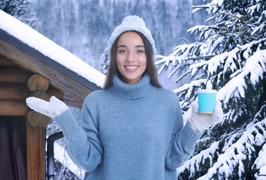 Image of Happy beautiful woman with mulled wine outdoors on snowy day 