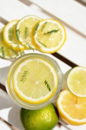 Photo of Delicious refreshing lemonade and pieces of citrus on white wooden table outdoors, flat lay