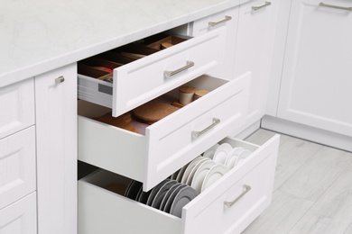 Open drawers with cutlery and utensils indoors. Order in kitchen