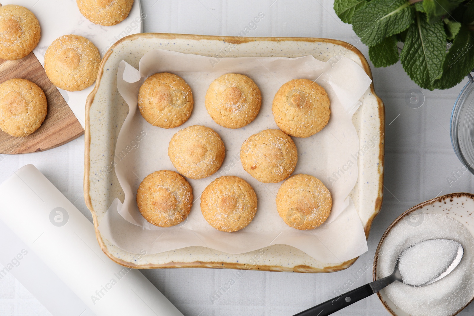 Photo of Tasty sweet sugar cookies in baking dish and mint on white tiled table, flat lay