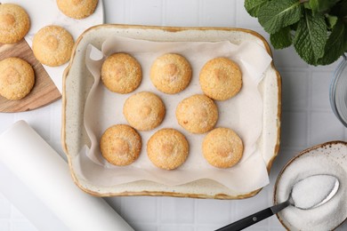 Photo of Tasty sweet sugar cookies in baking dish and mint on white tiled table, flat lay