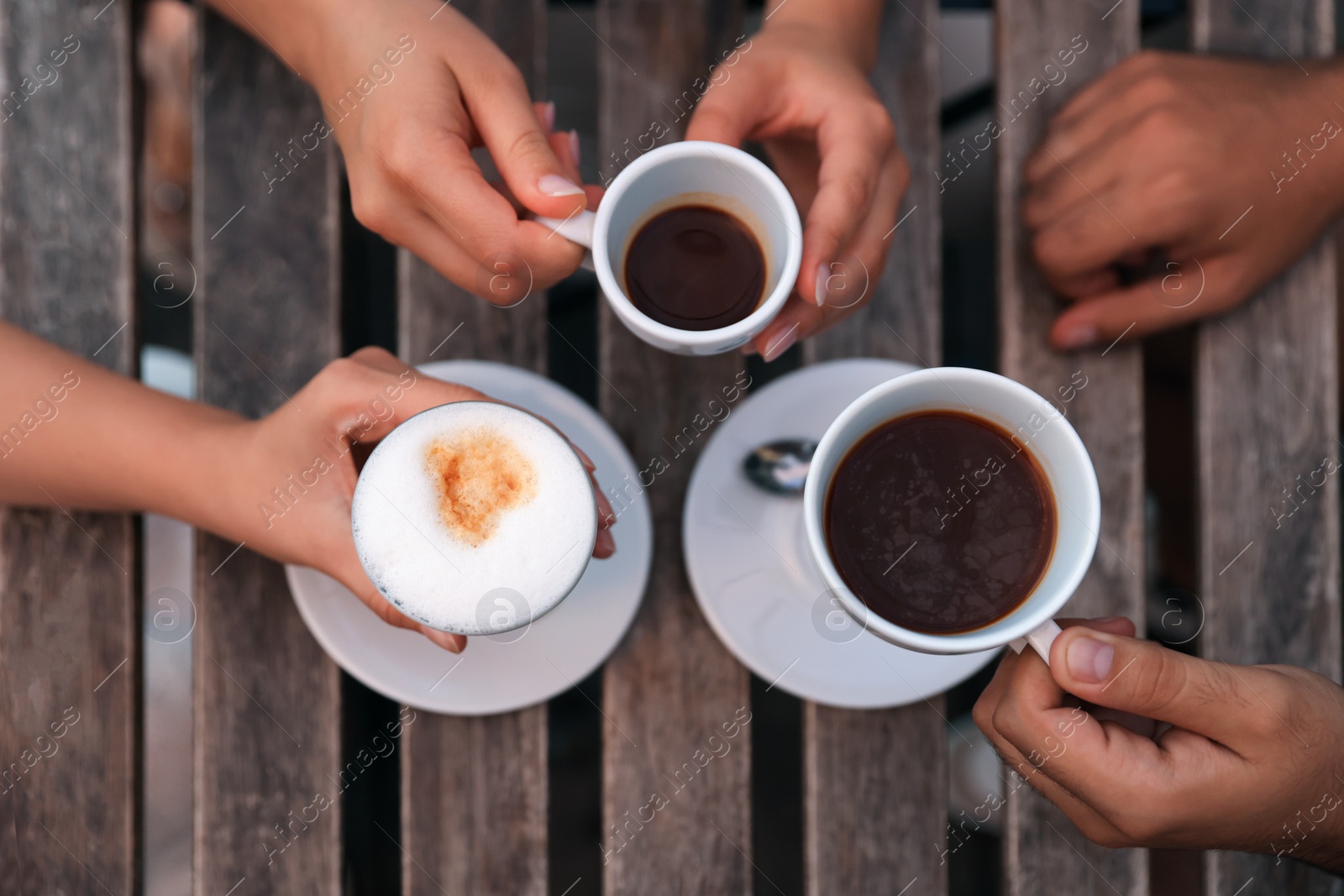 Photo of Friends drinking coffee at wooden table in outdoor cafe, above view