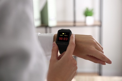 Woman measuring oxygen level with smartwatch indoors, closeup