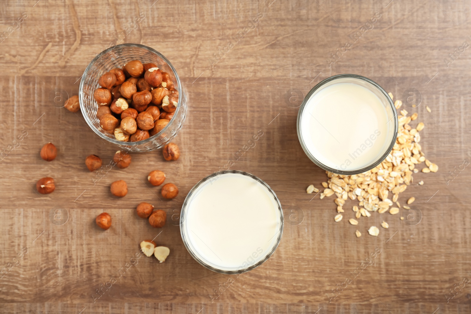 Photo of Glasses with hazelnut and oat milk on wooden background, top view