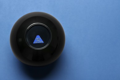 Photo of Magic eight ball with prediction Focus And Ask Again on blue background, top view. Space for text