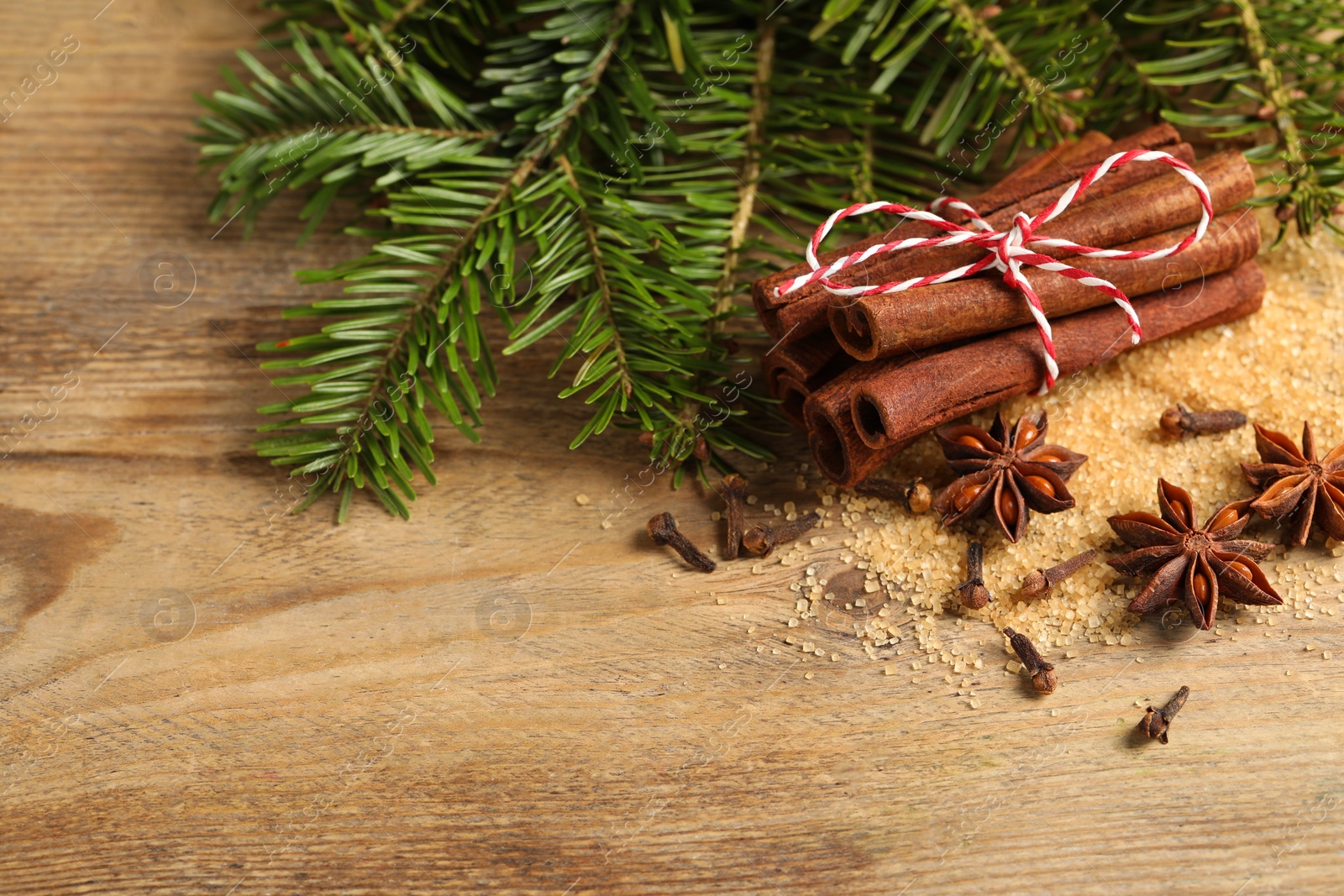 Photo of Different spices and fir branches on wooden table, flat lay. Space for text