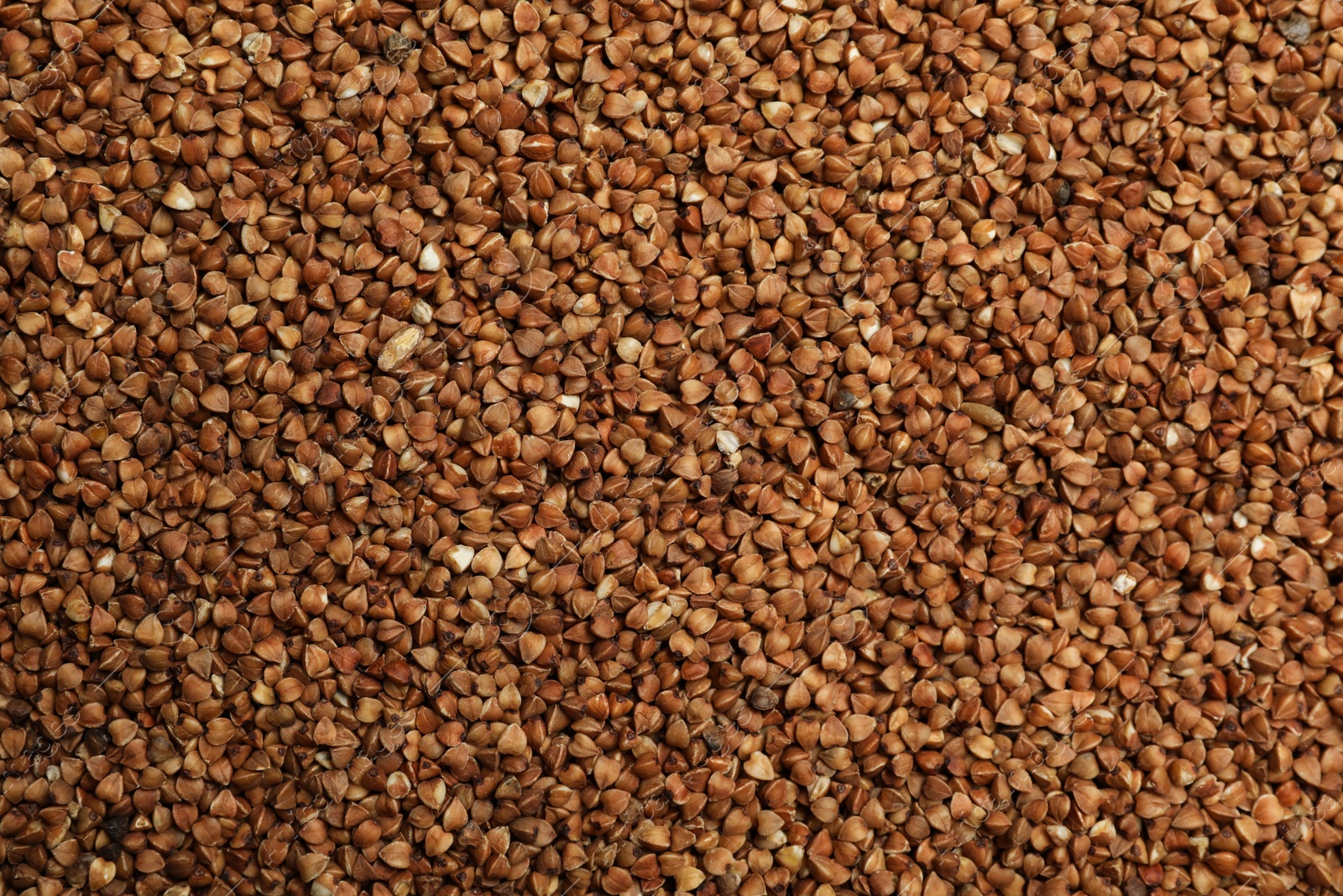 Photo of Uncooked buckwheat grains as background, top view