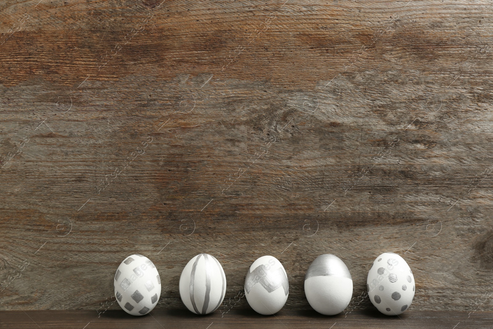 Photo of Painted Easter eggs on wooden background. Space for text