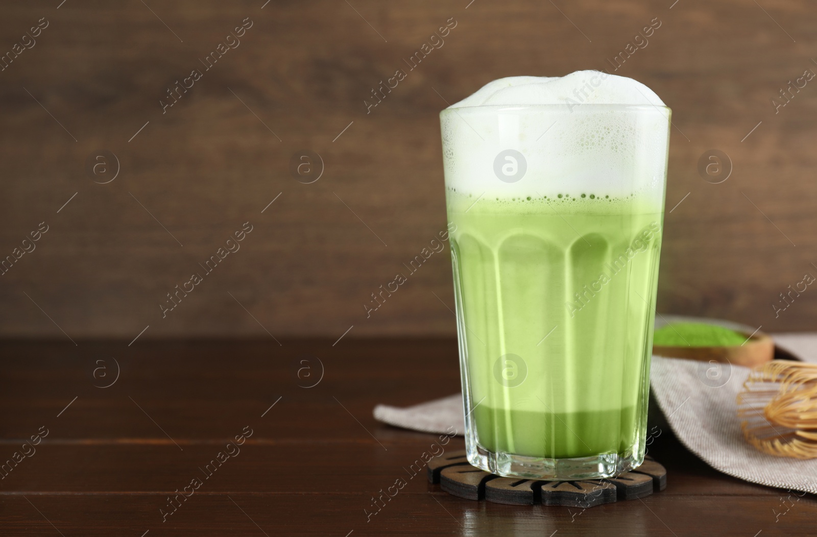 Photo of Glass of tasty matcha latte on wooden table. Space for text