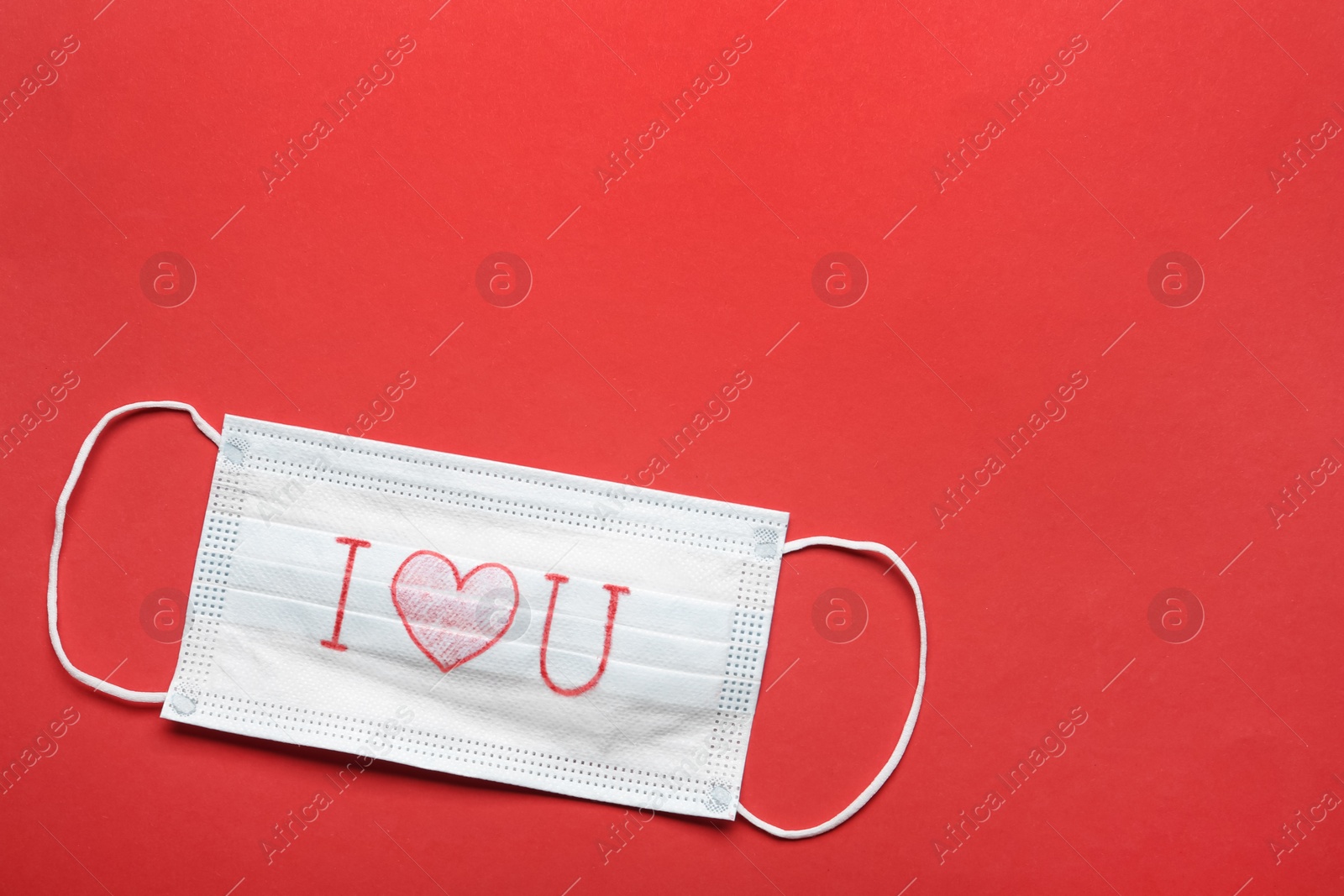 Photo of Medical mask with phrase I Love You on red background, top view. Space for text