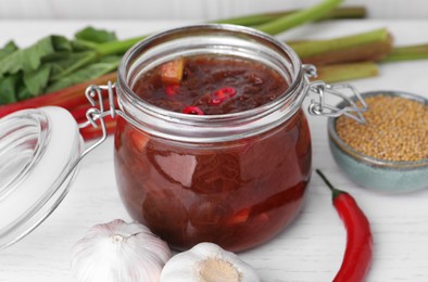 Photo of Tasty rhubarb sauce and ingredients on white table, closeup