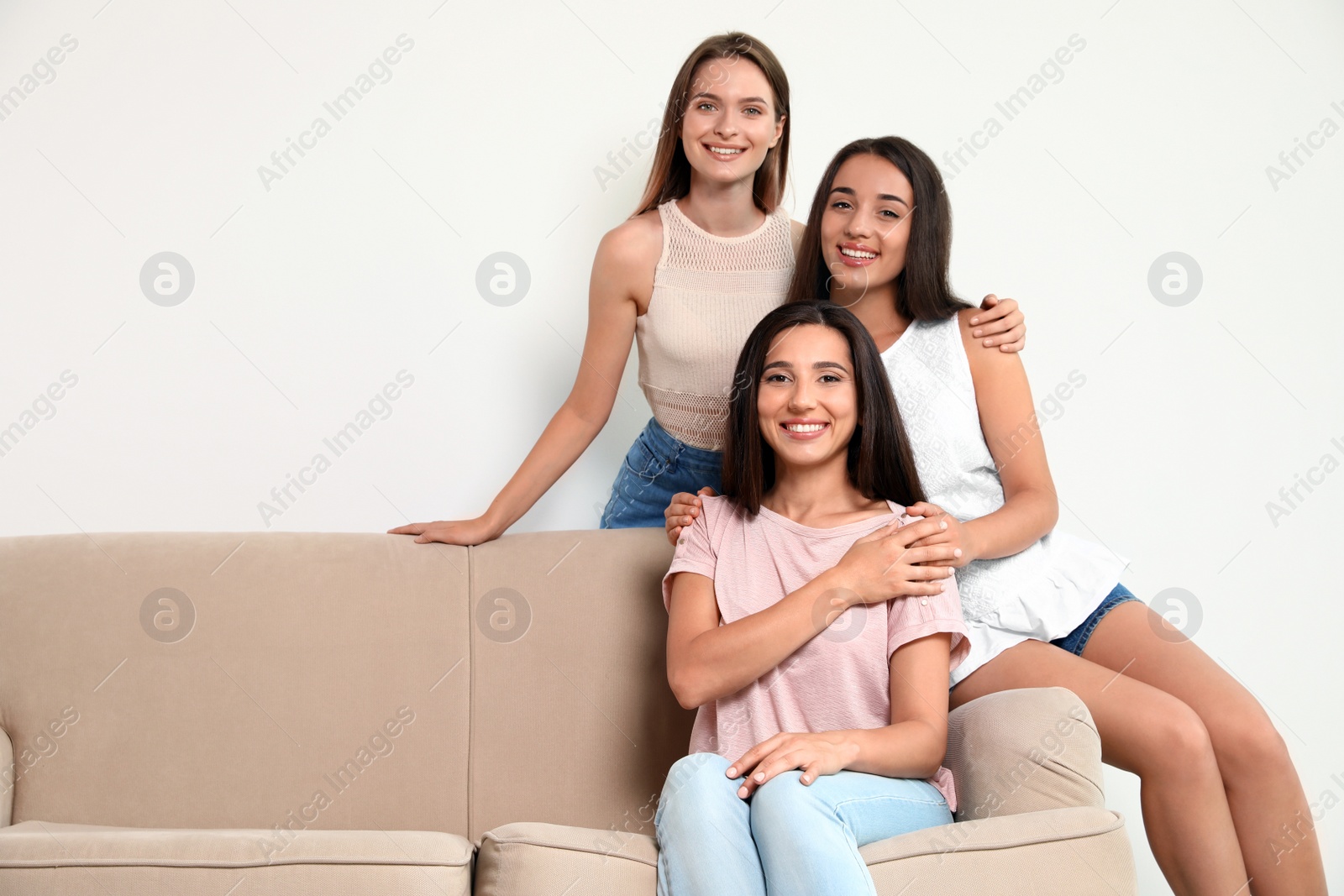 Photo of Happy women sitting on sofa near white wall, space for text. Girl power concept