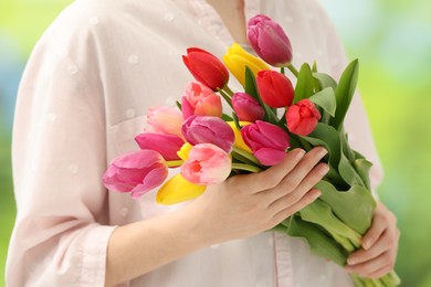 Photo of Woman holding beautiful colorful tulip flowers on blurred background, closeup