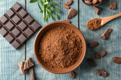 Photo of Flat lay composition with cocoa powder and chocolate bar on wooden background