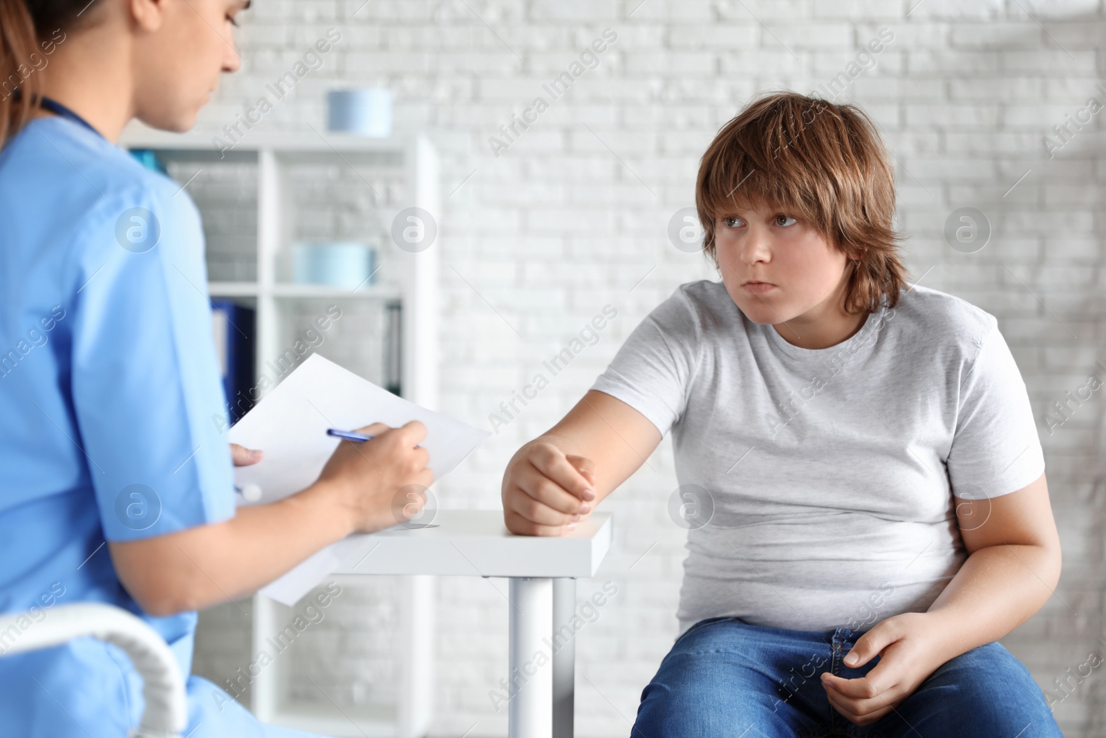 Photo of Overweight boy consulting with doctor in clinic