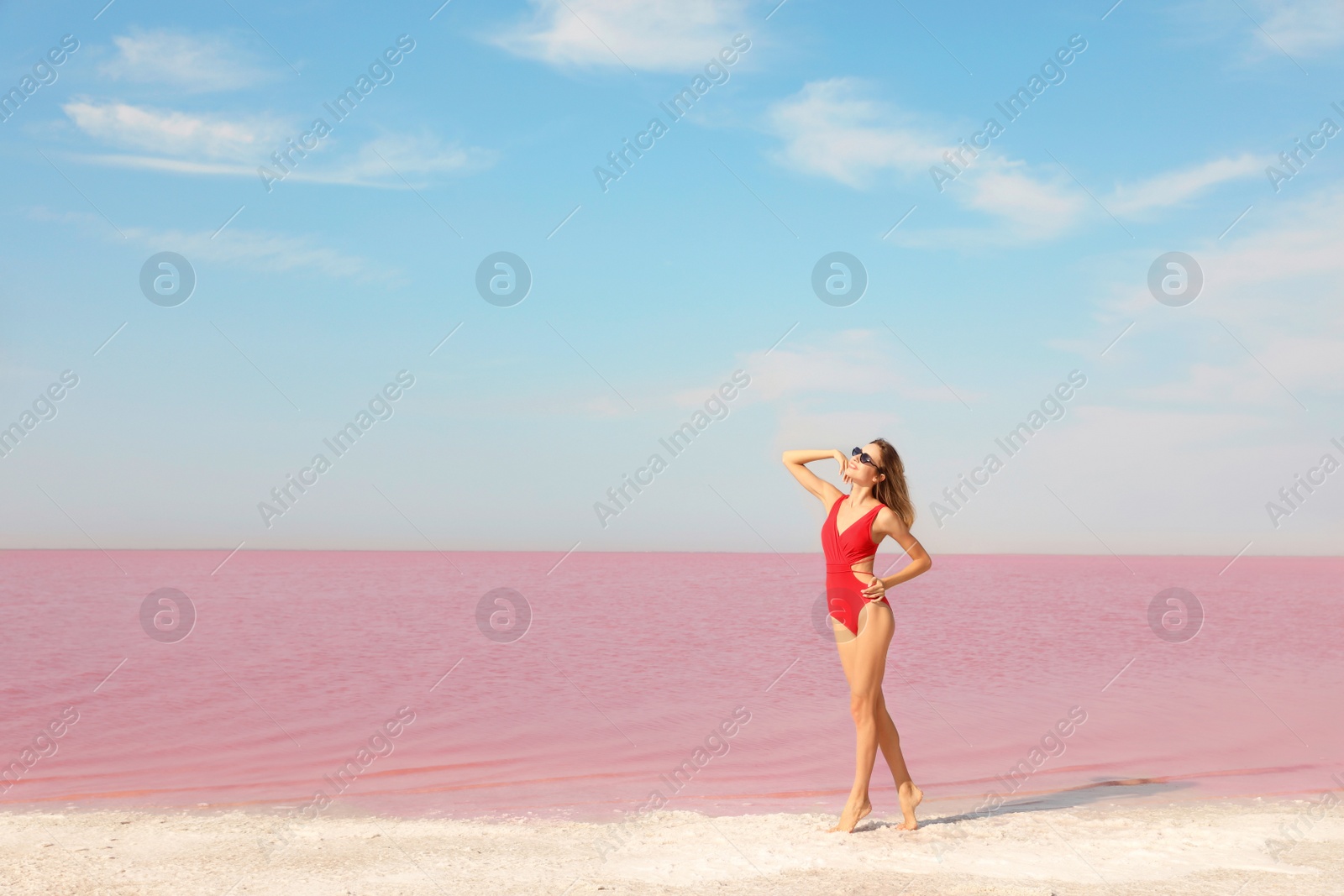 Photo of Beautiful woman in swimsuit posing near pink lake on sunny day