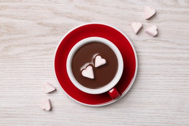 Cup of hot chocolate with heart shaped marshmallows on white wooden table, flat lay