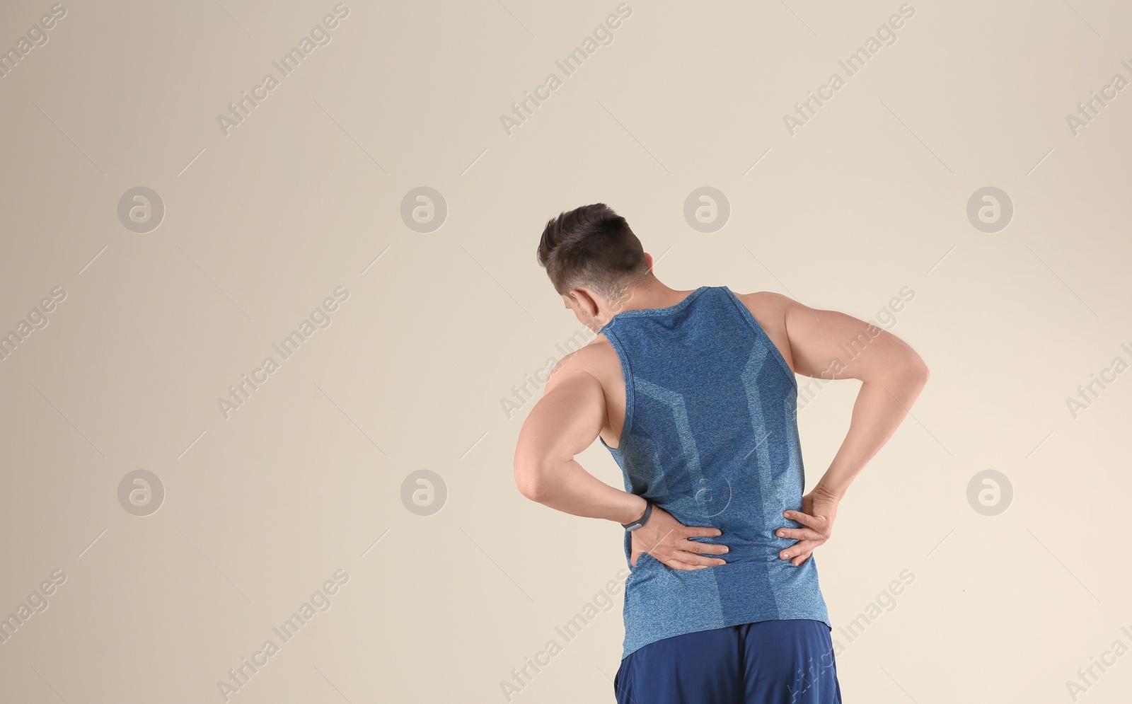 Photo of Man in sportswear suffering from back pain on light background