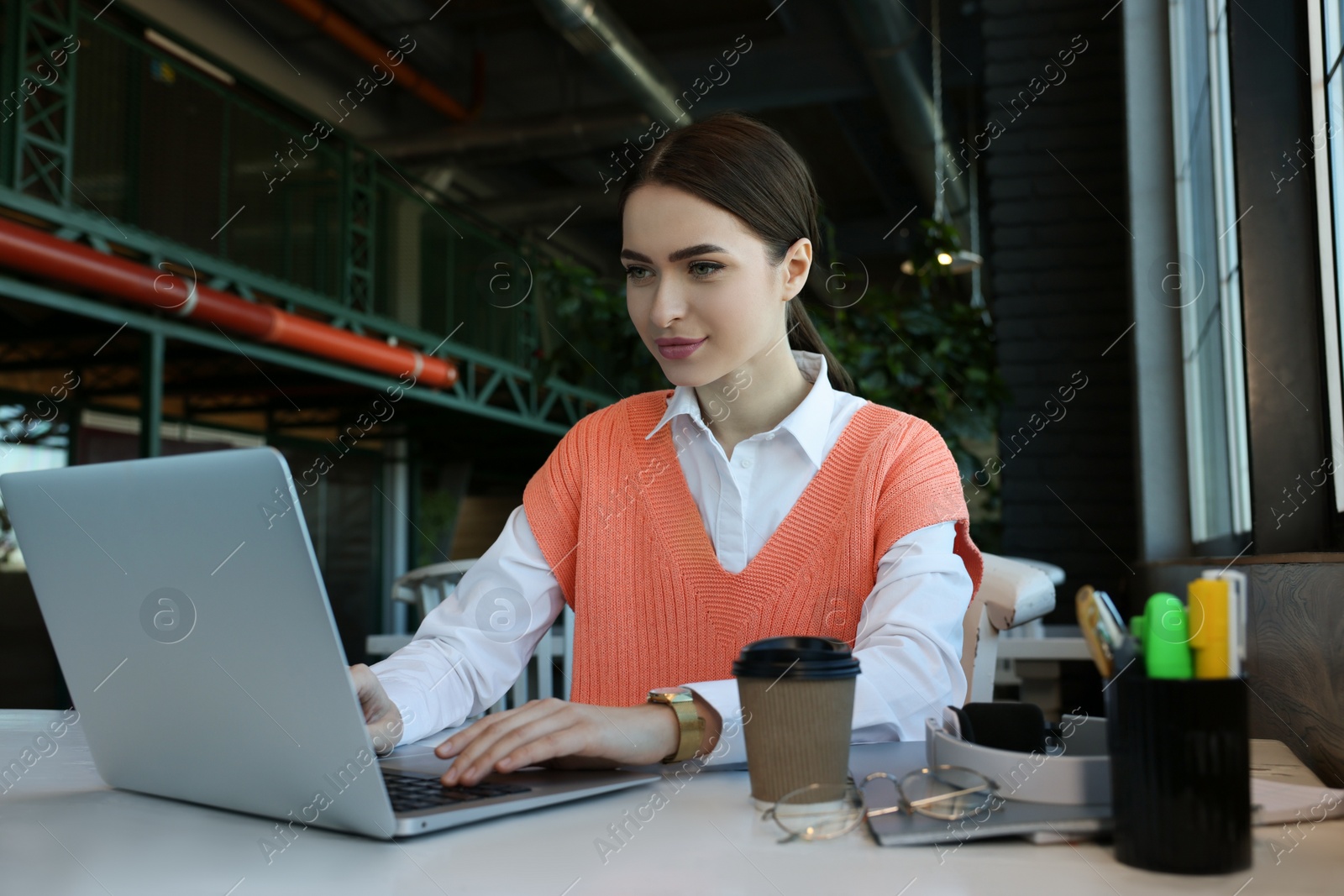 Photo of Young female student with laptop studying at table in cafe