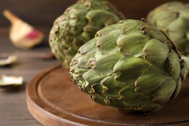 Fresh raw artichokes on wooden board, closeup