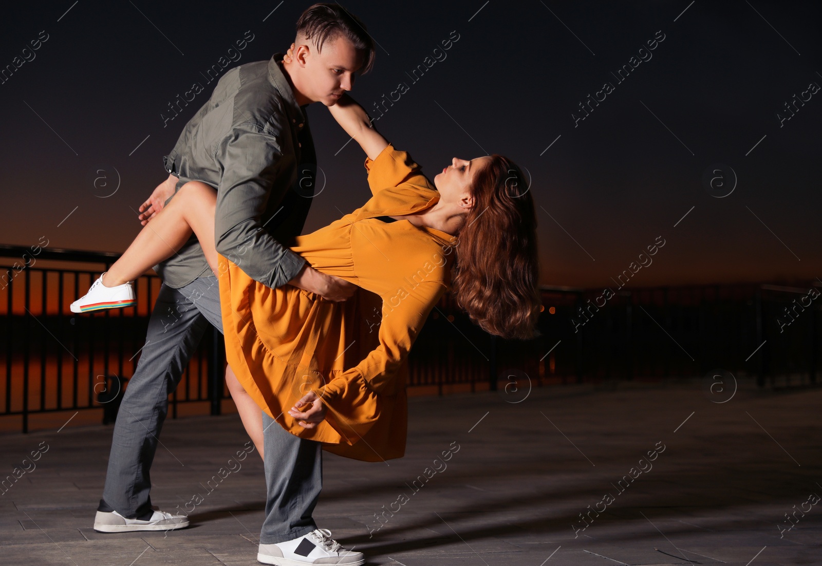 Photo of Beautiful young couple practicing dance moves in evening outdoors