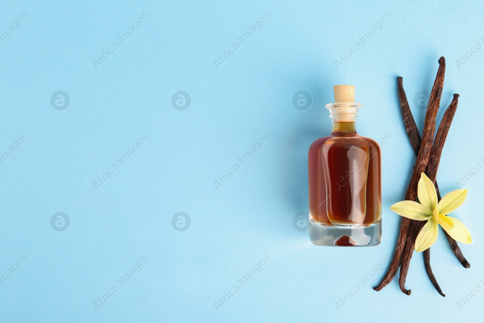 Photo of Flat lay composition with vanilla extract on light blue background. Space for text