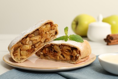 Photo of Delicious strudel with apples, nuts and raisins on table, closeup