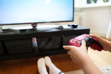 Photo of Child playing video games with controller at home, closeup