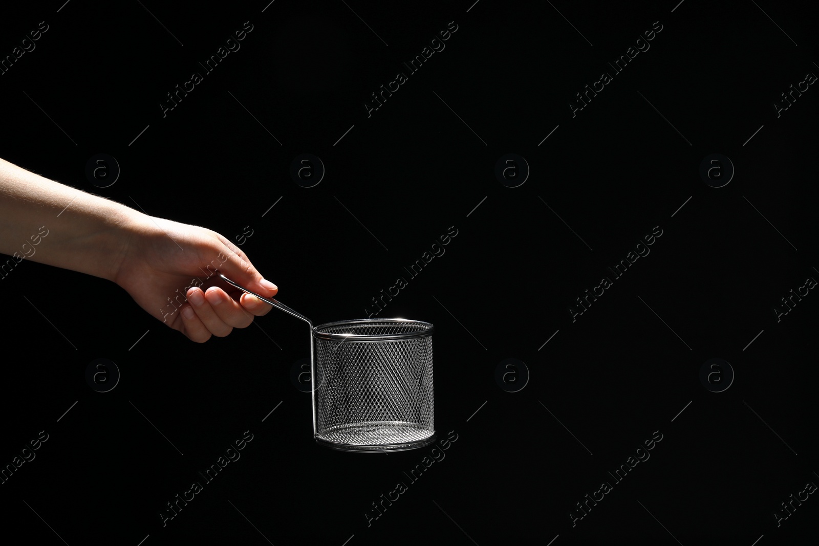 Photo of Woman holding metal basket for French fries on black background, closeup. Space for text