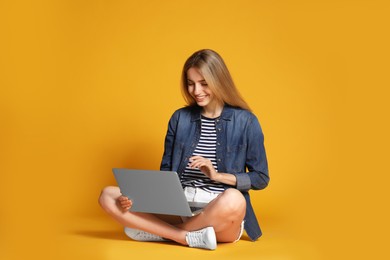 Photo of Young woman with laptop on yellow background