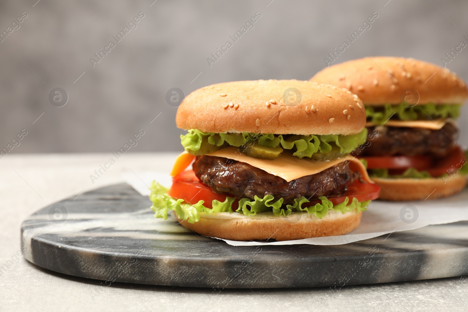 Photo of Tasty hamburgers with patties on light grey table, closeup