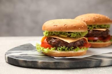 Photo of Tasty hamburgers with patties on light grey table, closeup
