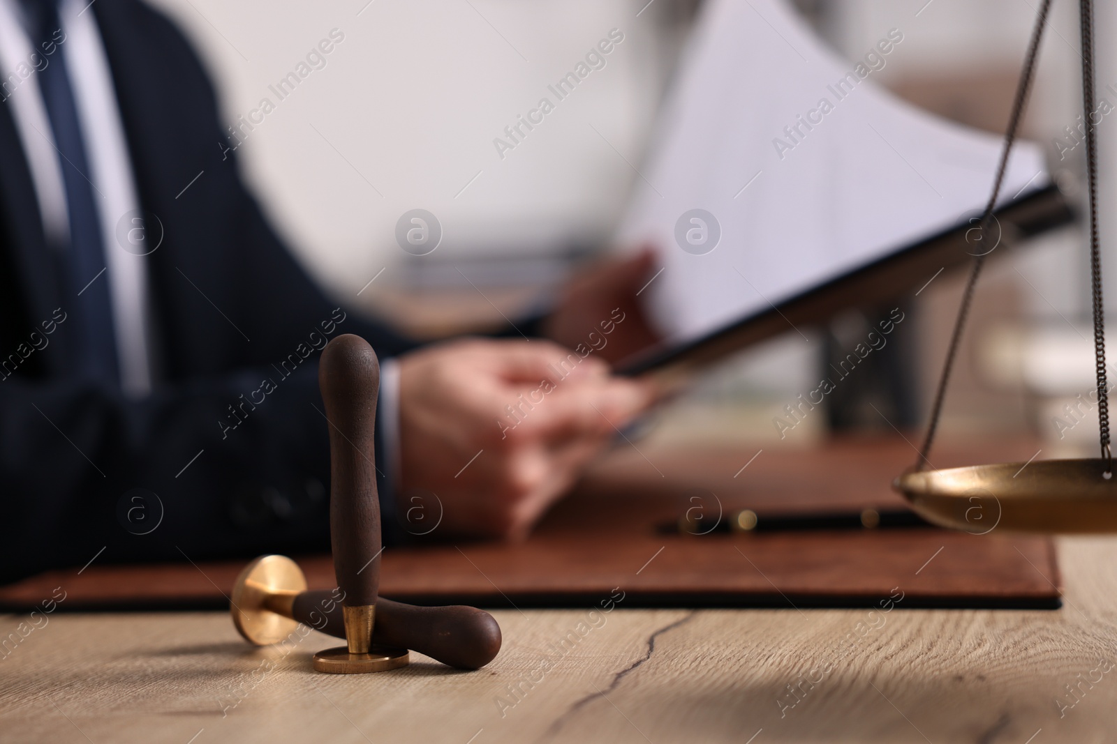 Photo of Notary working at wooden table in office, focus on wax stamps