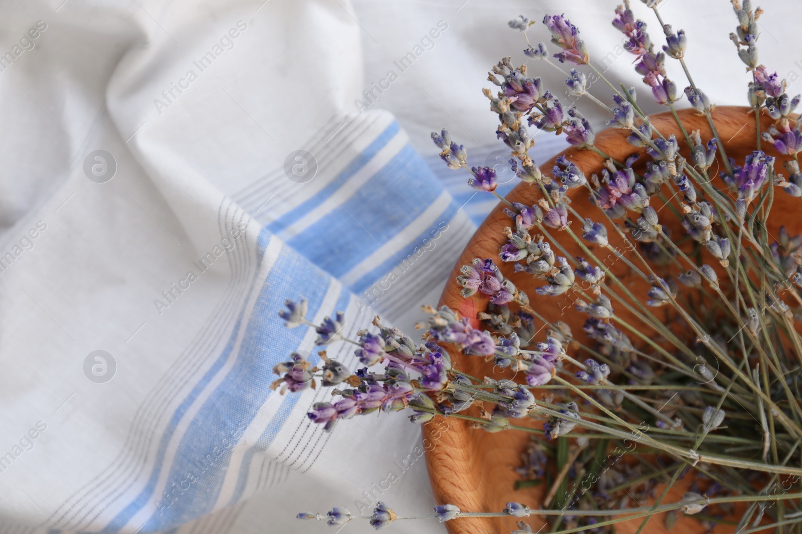 Photo of Bowl with beautiful lavender flowers on tablecloth, top view. Space for text