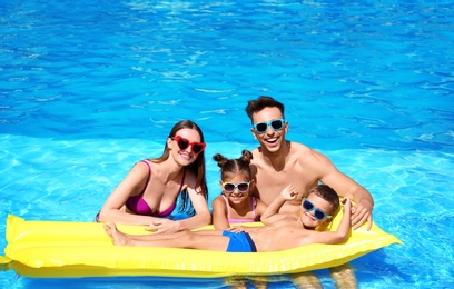 Photo of Happy family with inflatable mattress in swimming pool