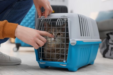 Photo of Travel with pet. Man closing carrier with cat indoors, closeup