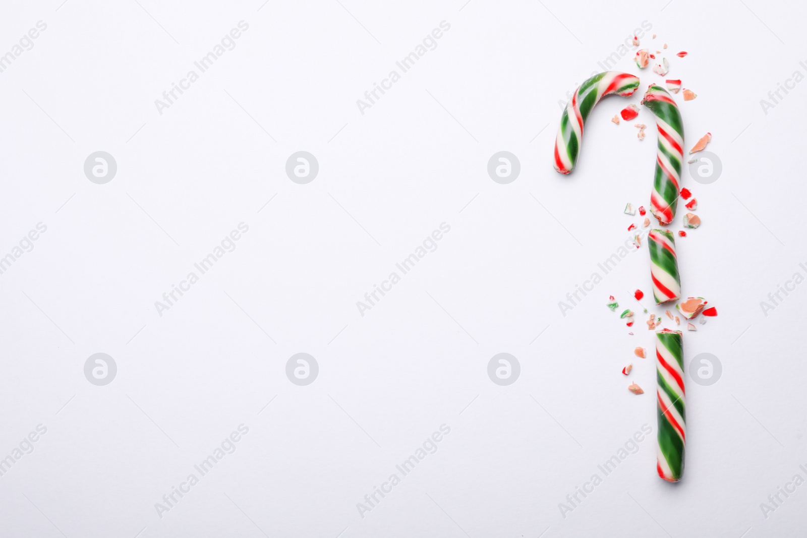 Photo of Broken sweet Christmas candy cane on white background, top view. Space for text