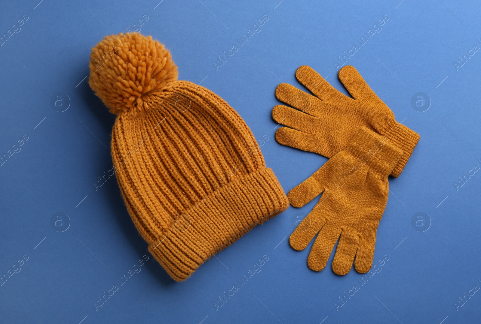 Photo of Woolen gloves and hat on blue background, flat lay