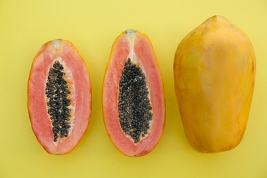 Fresh ripe cut and whole papaya fruits on light green background, flat lay