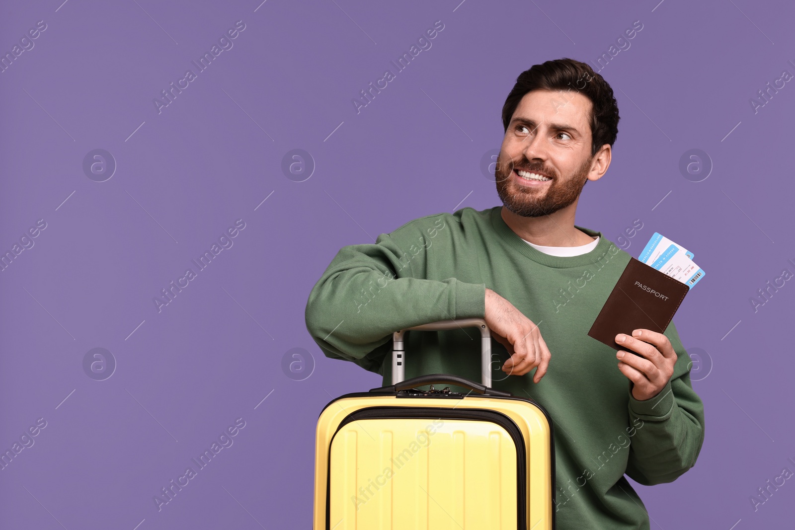 Photo of Smiling man with passport, tickets and suitcase on purple background. Space for text