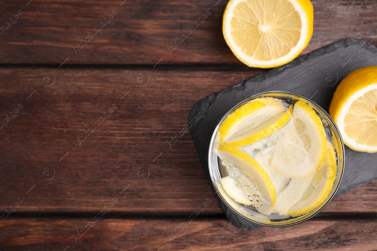 Photo of Soda water with lemon slices on wooden table, flat lay. Space for text