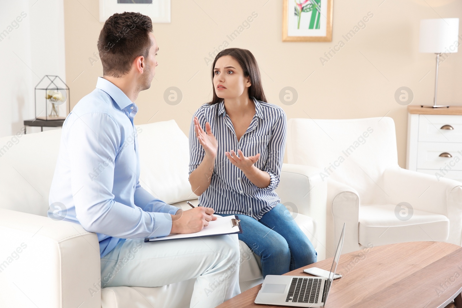 Photo of Depressed young woman having appointment with psychologist in office