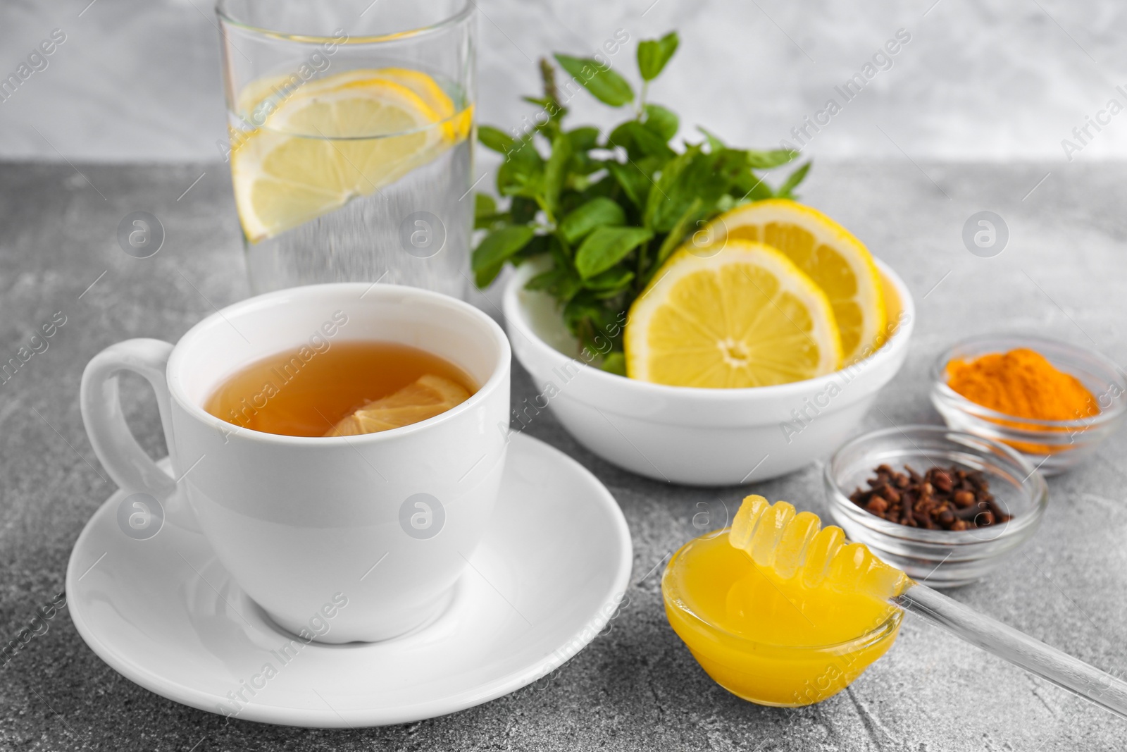 Photo of Cup with delicious immunity boosting tea and ingredients on grey table