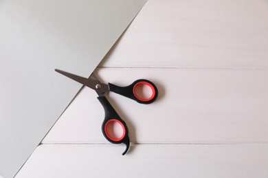 Photo of Scissors and paper on white wooden background, top view. Space for text