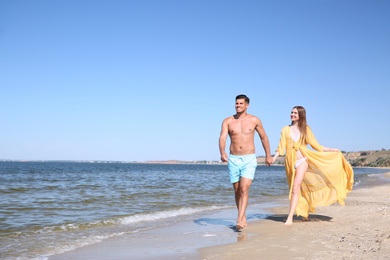 Photo of Woman in bikini and her boyfriend on beach, space for text. Happy couple